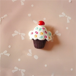 Macro shot of 3D resin cupcake charm with colorful sprinkles and red cherry topping