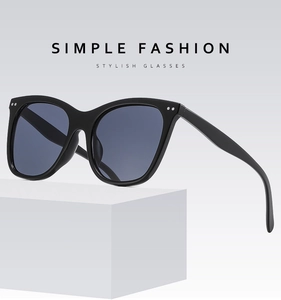 Detail of black oversized sunglasses with silver rivets on a white pedestal stand