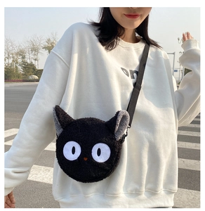 Detail of cute black plush cat shoulder bag with adjustable strap on white hoodie