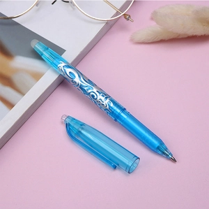 Detailed view of a blue erasable gel pen featuring silver dragon patterns on a pink desk