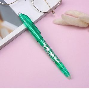 Detail of green retractable erasable pen with silver flame pattern on a pink background