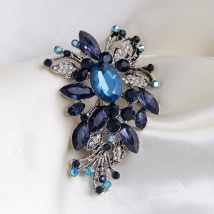 Broche florale vintage avec cristaux bleu roi et base en alliage argenté sur soie blanche
