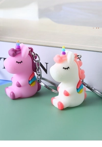 Close-up of cute pink and white PVC unicorn keychains with colorful wings and metal rings