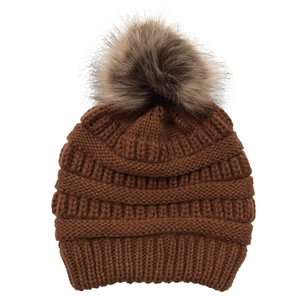 Detailed texture of brown winter knit beanie with a fluffy faux fur pompom decoration
