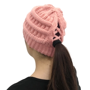 Detail showing the ponytail hole with criss-cross elastic design on pink knit beanie