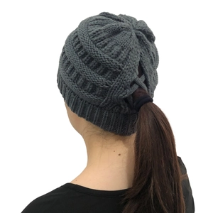 Detail view of the back of a dark grey knit ponytail beanie with a cross opening design