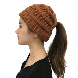 Detail shot of brown knit ponytail hat featuring a thick ribbed texture and functional opening