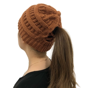 Detail showing the ponytail hole design on a caramel knit beanie for winter warmth