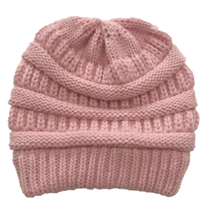 Detail of pink knitted beanie showing soft thick yarn texture and cross stitch pattern