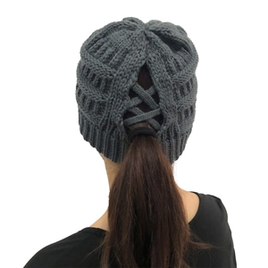 Detail view of dark grey knitted beanie with a practical criss-cross ponytail opening