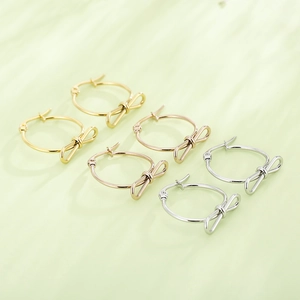 Boucles d'oreilles nœuds chics en finitions or, or rose et argent sur fond vert