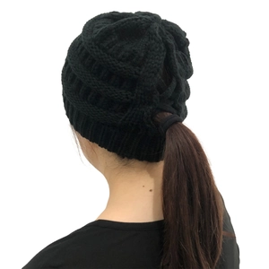 Detail view of the back ponytail hole design on black knitted winter beanie hat