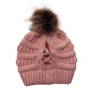 Nahaufnahme der rosa Strickmütze mit abnehmbarem flauschigen Bommel und Zopf-Loch-Detail.