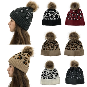Detail of leopard print knit beanie featuring a faux fur pompom and rolled cuff