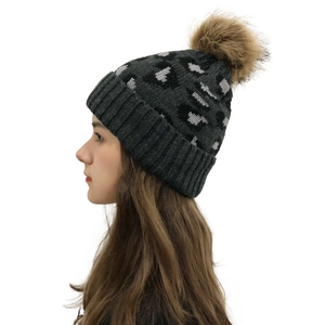 Detail of grey leopard print knitted beanie featuring a fluffy brown faux fur pom pom