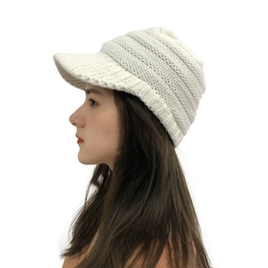 Side view of white cable knit peak beanie showing textured stitch and curved brim