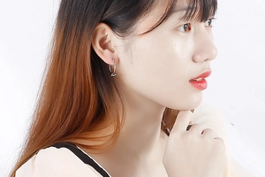 Gros plan d'une boucle d'oreille créole argentée avec nœud portée par un mannequin