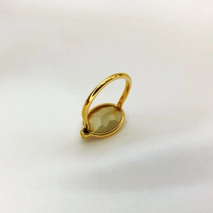 Vue de dessus d'une bague dorée avec une pierre précieuse jaune sur un tissu texturé