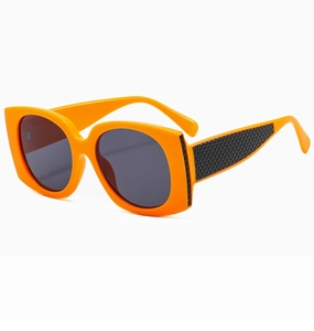 Close-up of orange oversized sunglasses featuring textured black diamond pattern on wide temples