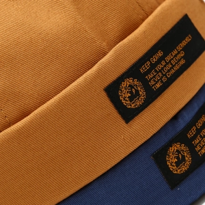 Detail of cotton street style brimless docker caps with embroidered quote labels