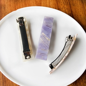 Detailed view of acetate leopard print hair clips with metal spring mechanism on ceramic plate