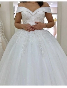 Détail d'une robe de mariée à col en V, épaules dénudées avec dentelle et sequins brillants