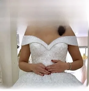 Détail de robe de mariée blanche à épaules dénudées avec broderie de sequins et perles