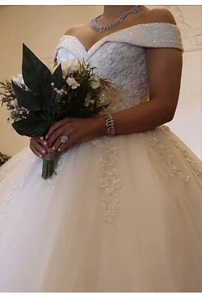 Vue détaillée de la robe de mariée en dentelle à épaules dénudées avec fleurs et bouquet