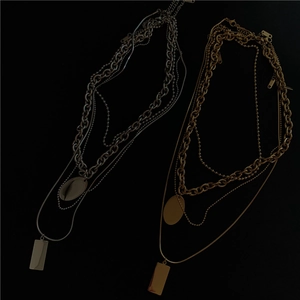 Detailed view of layered gold and silver chains featuring oval and geometric pendants