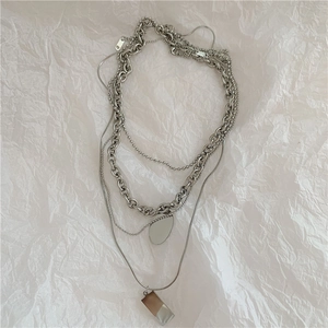 Detail of multi-layered silver necklace with bead chain and geometric pendants