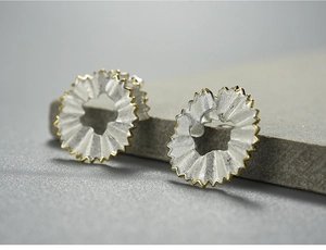 Macro shot of silver pencil shavings earring with elegant gold edge and brushed texture