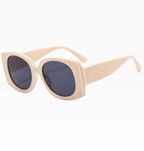 Detail of beige sunglasses featuring oversized frame and textured scale pattern on temples