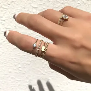 Detail shot of five stacked gold rings including pear-shaped stone and chain texture