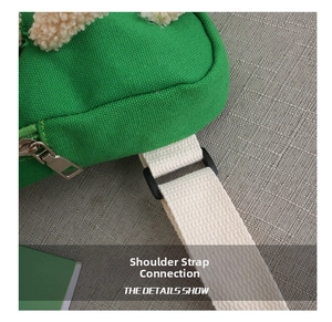 Detailed close-up of the shoulder strap connection and white cotton webbing on green bag