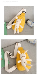 Detail of a bright yellow canvas chest bag with a plush bunny and adjustable strap