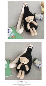 Detail of black canvas chest bag featuring a 3D teddy bear doll and wide strap