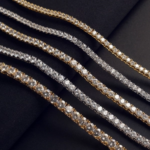Macro shot of silver and gold tennis chains with round cubic zirconia on dark fabric