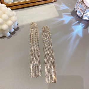 Close-up of sparkling silver tassel earrings with crystal rhinestones on grey leather
