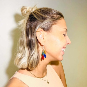 Colorful neon light bulb drop earrings for Christmas worn by a model in a profile shot