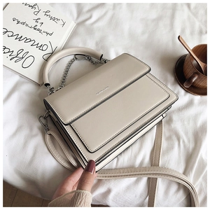Detail of off-white leather handbag showing fine texture and fashion chain handle