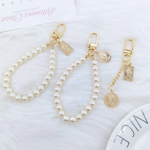 Detailed shot of retro gold coins and pearl keychains on a soft white plush surface