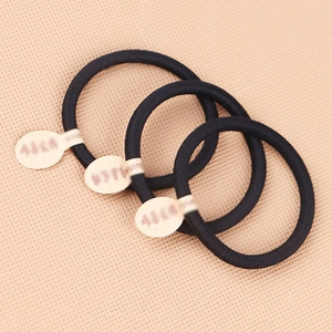 Detailed view of three black elastic hair ties on a textured fabric background