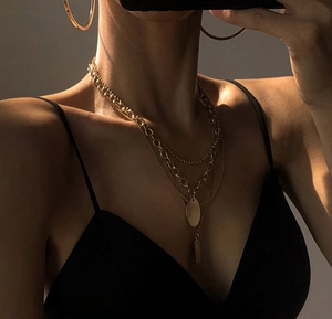 Close-up of layered gold titanium steel necklaces with circular and rectangular pendants