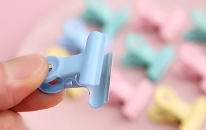 Close-up of a blue macaron bulldog clip held by hand for creative DIY and stationery use