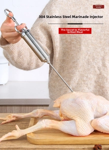 Détail d'une seringue à marinade en acier 304 injectant des saveurs dans un poulet entier
