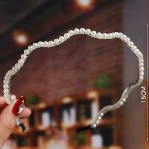 Macro detail of 15cm pearl headband with silver metal frame and wavy design