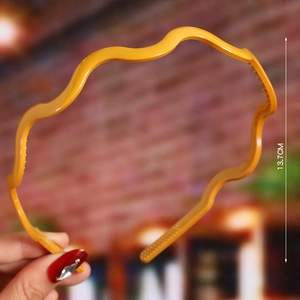 Detailed view of 13.7cm yellow wavy plastic headband showing dimensions and glossy texture