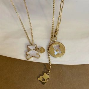 Detail of gold-plated stainless steel necklaces with white shell bear and heart pendant