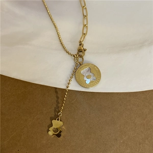 Detail of gold necklace featuring white mother-of-pearl bear pendant and heart charm