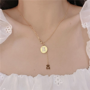 Detail of asymmetric gold bear necklace showing mother of pearl pendant on white blouse
